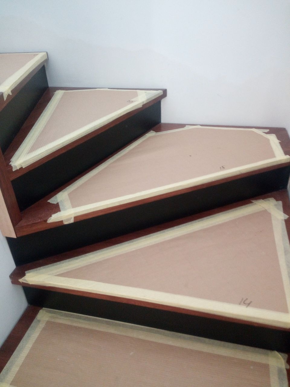 Drewniane schody w trakcie montażu, zabezpieczone taśmą malarską, widoczne numery stopni.