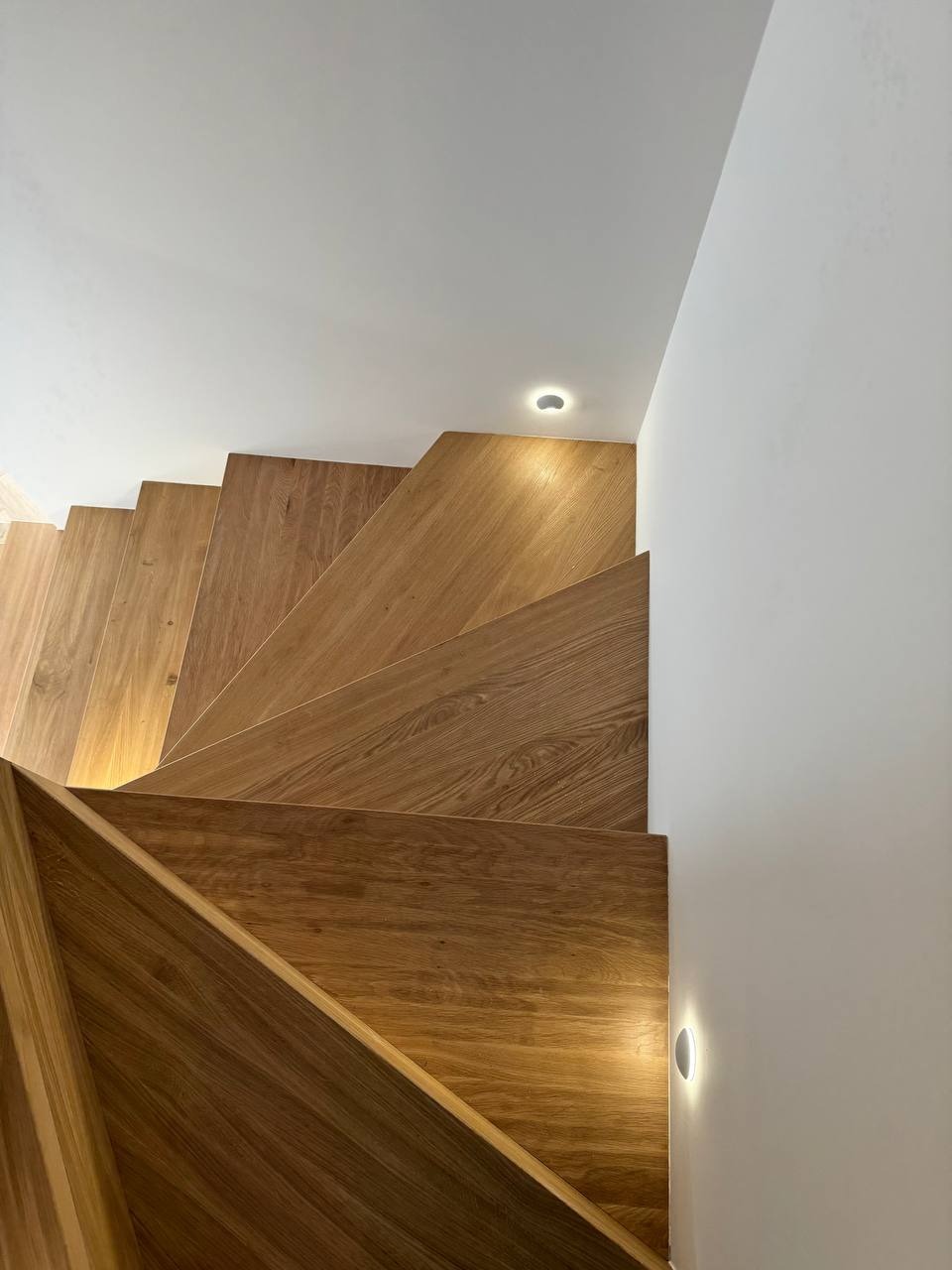 Nowoczesne, drewniane schody z oświetleniem punktowym w Gdańsku, widok z góry, minimalistyczny design z jasnego drewna.