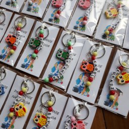 Beztroski Świat - Ręcznie robione breloczki z imionami, zawieszkami w kształcie sowy i kolorowymi koralikami, zapakowane w foliowe woreczki z kartonikami z motywem ucznia.