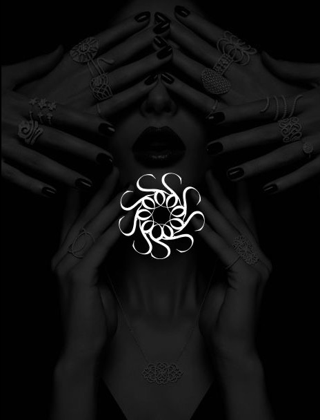 Kobieta z ciemnymi ustami i paznokciami, zasłaniająca oczy dłońmi z pierścionkami, z abstrakcyjnym białym ornamentem na dekolcie i naszyjnikiem z motywem kwiatowym.