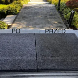 Wyraźny podział na 'przed' i 'po' na wycieraczce w Krakowie, z widoczną r&oacute;żnicą w czystości i kolorze, umieszczonej na tle kamiennej ścieżki w ogrodzie.