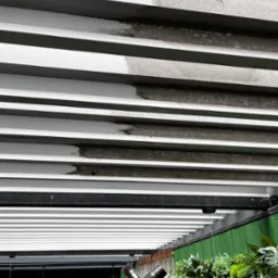 Szczegółowe ujęcie fragmentu czyszczonej, białej, poziomej żaluzji sufitowej, ukazujące różnicę między obszarem przed i po zabiegu. Widoczne zabrudzenia i świeżo umyta powierzchnia.