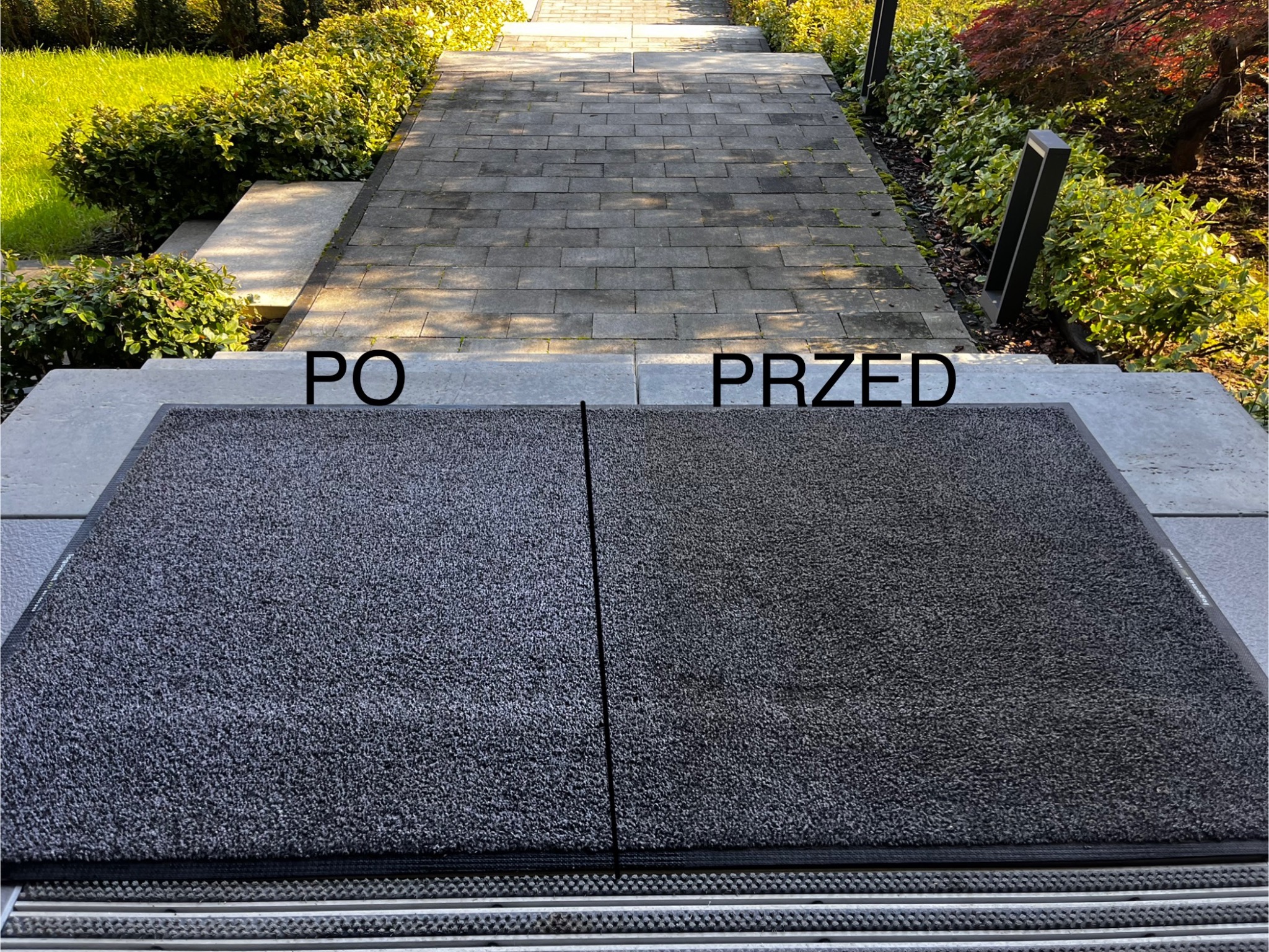 Wyraźny podział na 'przed' i 'po' na wycieraczce w Krakowie, z widoczną różnicą w czystości i kolorze, umieszczonej na tle kamiennej ścieżki w ogrodzie.