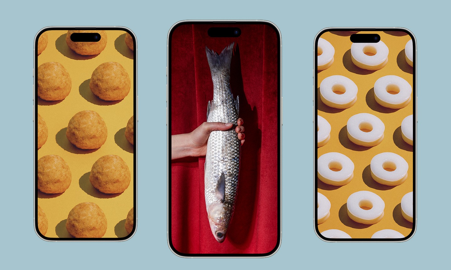 Trzy telefony z różnymi tapetami: kulki na żółtym tle, ryba trzymana na tle czerwonej zasłony i oponki na żółtym tle.