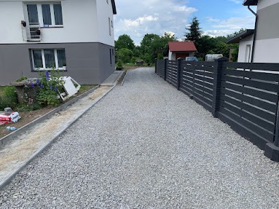 Nowo utwardzona droga żwirowa w Rzeszowie, widoczna posesja z nowoczesnym ogrodzeniem panelowym i fragmentem budynku z klimatyzacją.