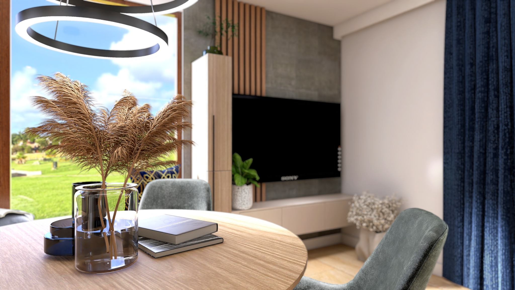 Stół z drewnianym blatem, wazon z suszonymi trawami, książki i widok na zielony ogród przez okno; w tle telewizor na ścianie z drewnianymi panelami.