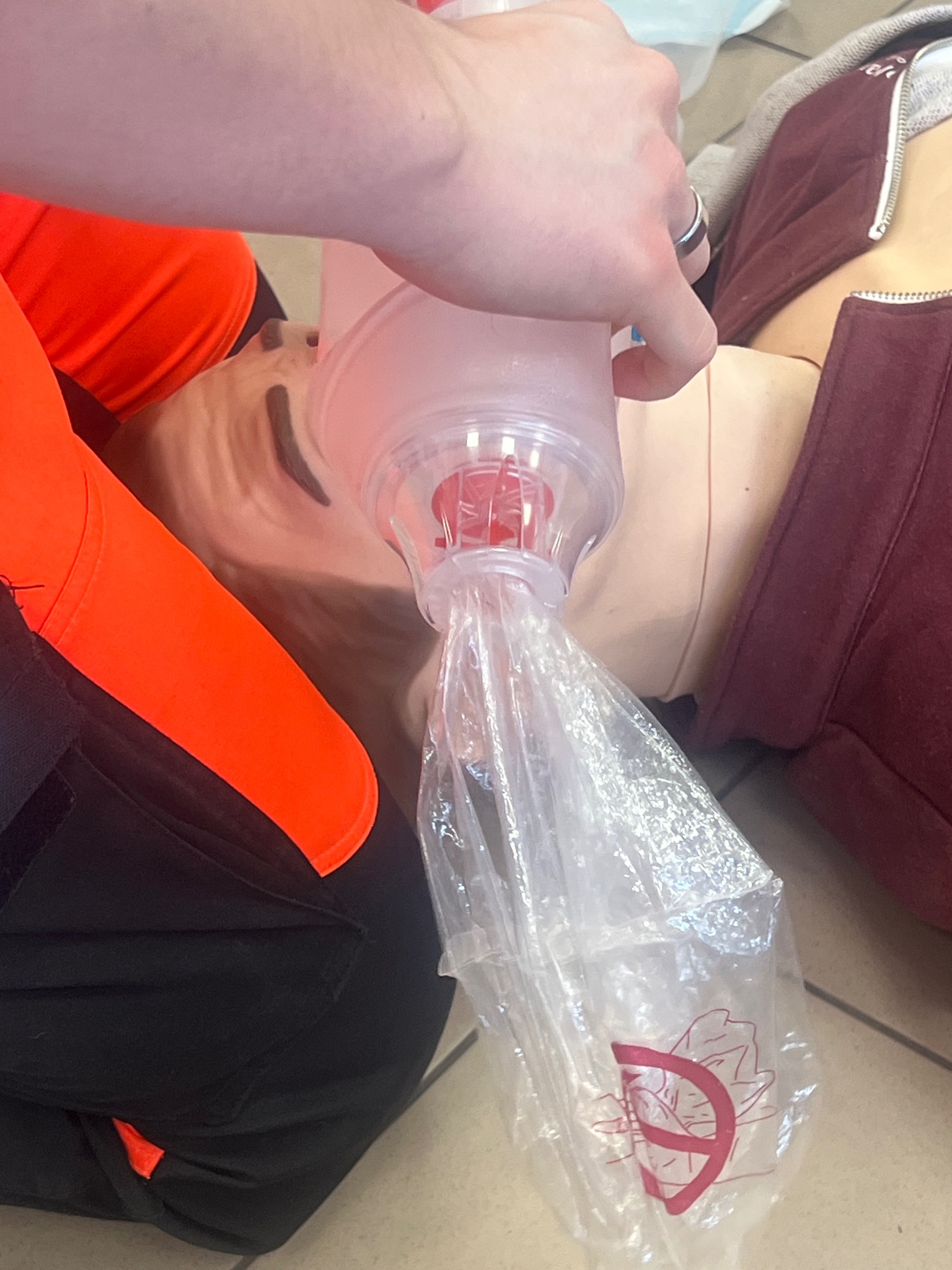 Manekin podczas resuscytacji usta-usta z użyciem worka samorozprężalnego. Widoczna dłoń, worek, manekin w ubraniu. Szkolenie z pierwszej pomocy.