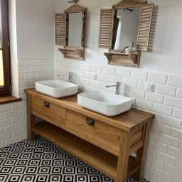 Mazurska Pracownia Drewna Dorota Kowalczyk - Łazienka z dwiema białymi umywalkami nablatowymi na drewnianej szafce z szufladami i półką, nad którymi wiszą lustra w drewnianych ramach z okiennicami, białe płytki na ścianach i wzorzysta...
