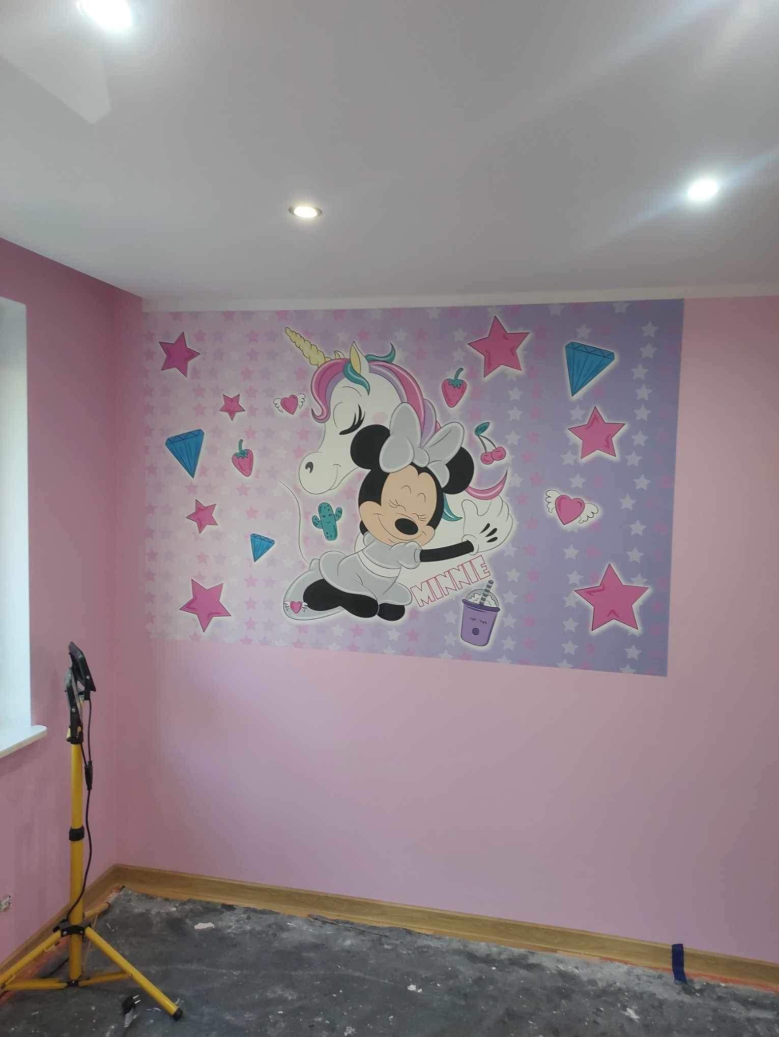 Różowa ściana w pokoju dziecięcym z naklejką przedstawiającą Minnie Mouse i jednorożca na tle gwiazd, widoczna lampa budowlana i surowa podłoga przed ułożeniem paneli.