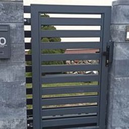 ALUM-STAL ARKADIUSZ STUDNIARZ - Nowoczesna brama wjazdowa z poziomymi przęsłami, osadzona między murowanymi słupkami z szarego betonu, jeden z nich z zamontowaną skrzynką na listy z numerem 10.