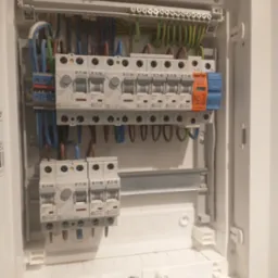 Rozdzielnica elektryczna Eaton z zainstalowanymi bezpiecznikami i przewodami. Widoczne okablowanie w kolorach: niebieskim, brązowym, zielono-żółtym, pomarańczowym.