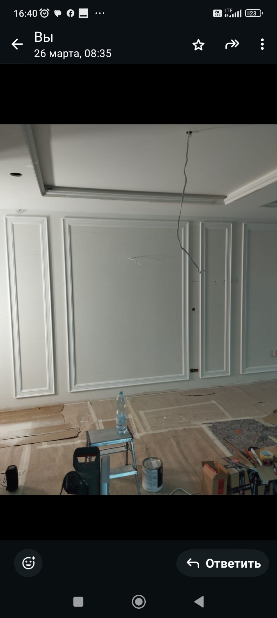 Białe, ozdobne listwy ścienne w klasycznym stylu, zamontowane na ścianie w trakcie prac wykończeniowych. Na podłodze kartony ochronne i narzędzia.