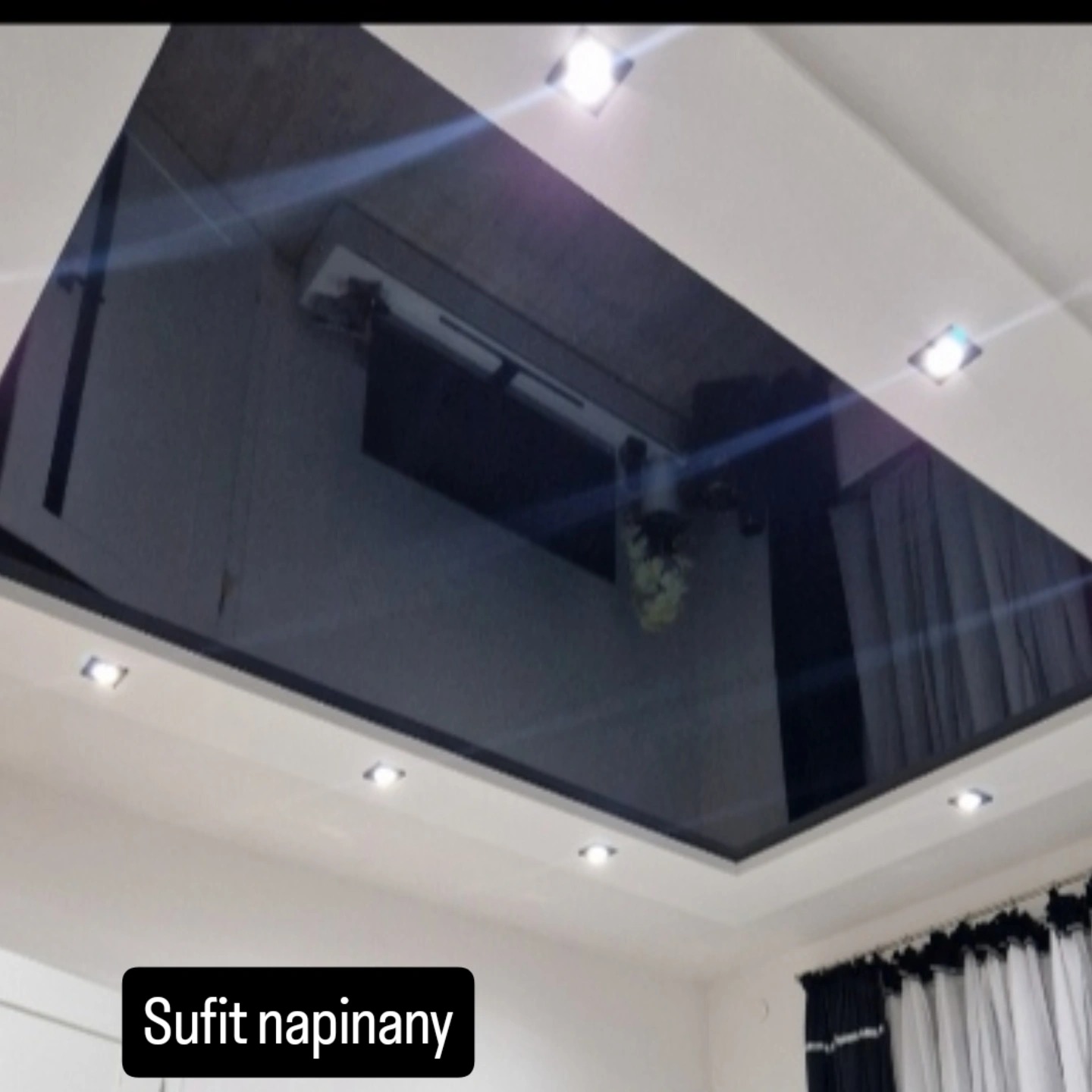 Błyszczący, czarny sufit napinany z oświetleniem punktowym, odbijający wnętrze w Szprotawie. Nowoczesny design, gładka powierzchnia, eleganckie wykończenie.