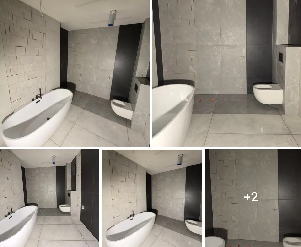 Nowoczesna łazienka z wolnostojącą wanną, szarą płytką imitującą kamień i czarnymi akcentami. Widoczne pomarańczowe kliny glazurnicze na podłodze.