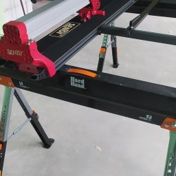 Instalpos - Profesjonalna przecinarka do płytek ceramicznych marki Sendi na regulowanym stole roboczym Hard Head, gotowa do użycia w pomieszczeniu w trakcie remontu.