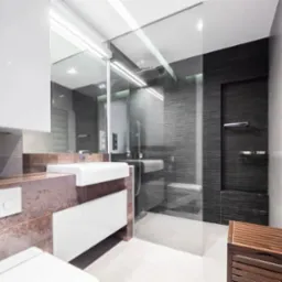 Nowoczesna łazienka z kabiną prysznicową typu walk-in, umywalką nablatową na blacie z efektem rdzy i czarnym grzejnikiem drabinkowym.