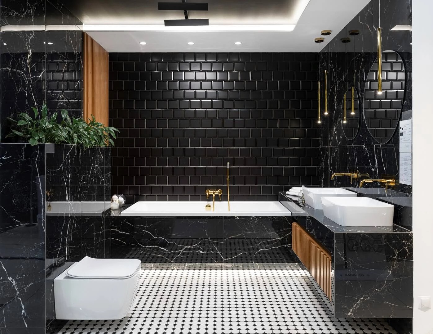 Elegancka łazienka z czarnymi płytkami metra, marmurowymi ścianami i podłogą w biało-czarną mozaikę, złota armatura, dwie białe umywalki i wisząca toaleta.