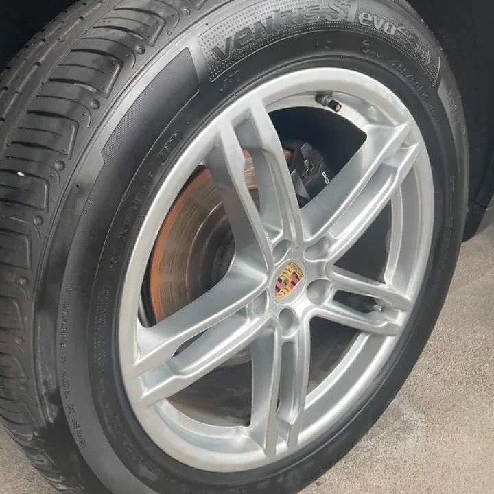 Błyszcząca, srebrna felga z oponą Ventus S1 evo, widoczna tarcza hamulcowa z logo Porsche w tle.