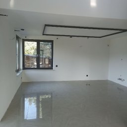 ROMAN SAVCHYSHYN - Nowoczesne wnętrze z szarymi płytkami podłogowymi, dużym oknem z widokiem na zieleń i minimalistycznym oświetleniem sufitowym.