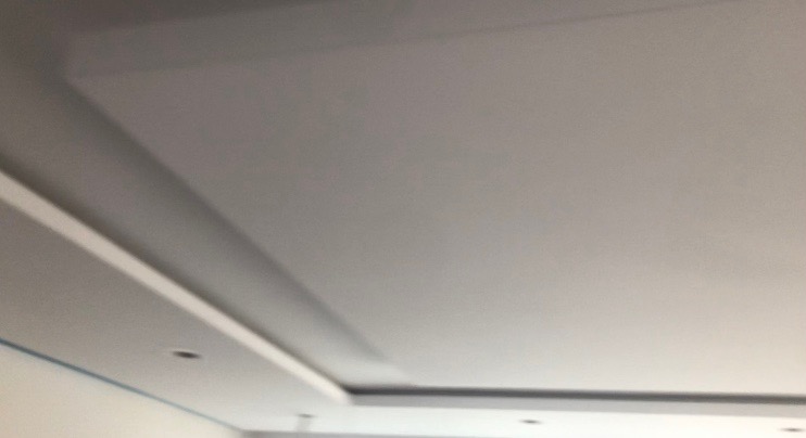 Wykończony sufit podwieszany z oświetleniem punktowym, widok z dołu, minimalistyczny design.