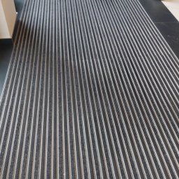 FUNDACJA NOSTRA - Szara wycieraczka systemowa z aluminiowymi listwami przed schodami wejściowymi do budynku.