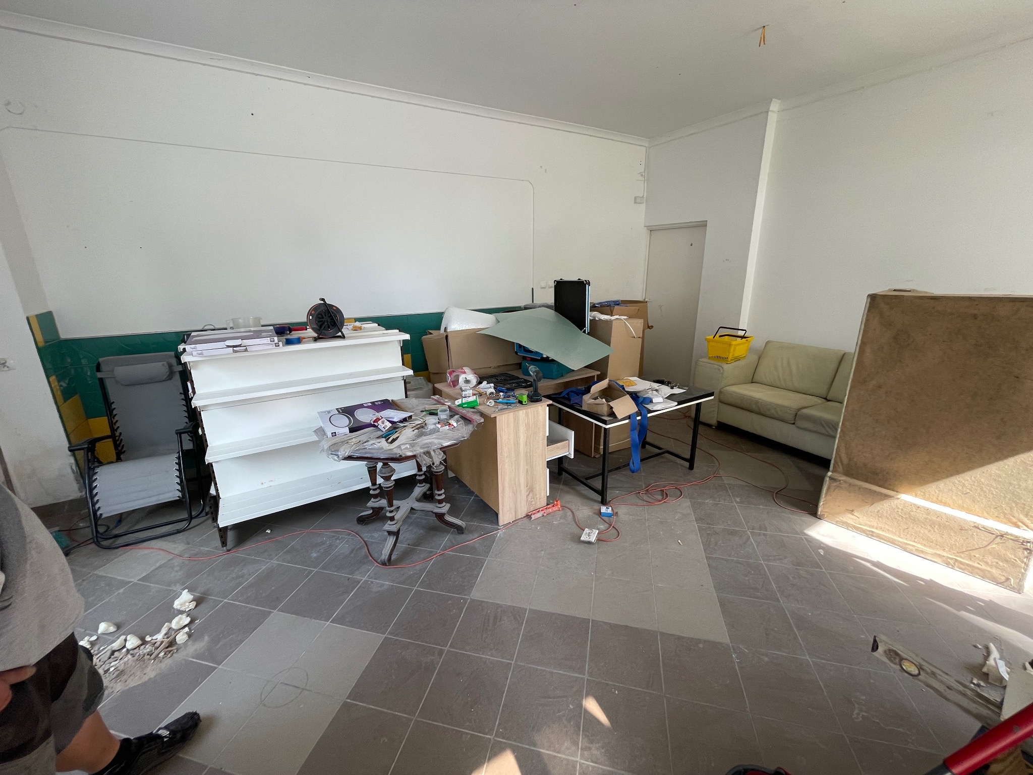 Pokój w trakcie przygotowań do transportu: meble, kartony i akcesoria zgromadzone w jednym pomieszczeniu, widoczne ślady demontażu na podłodze.