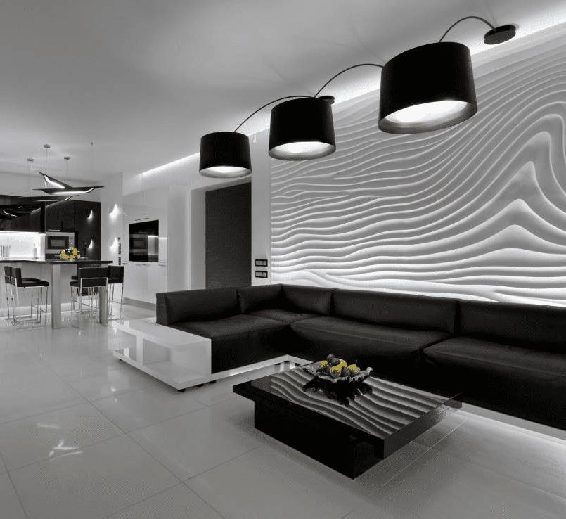 Nowoczesne wnętrze salonu z czarną skórzaną sofą narożną, stolikiem kawowym z owocami i trójką czarnych lamp wiszących nad falistą, podświetlaną ścianą 3D.