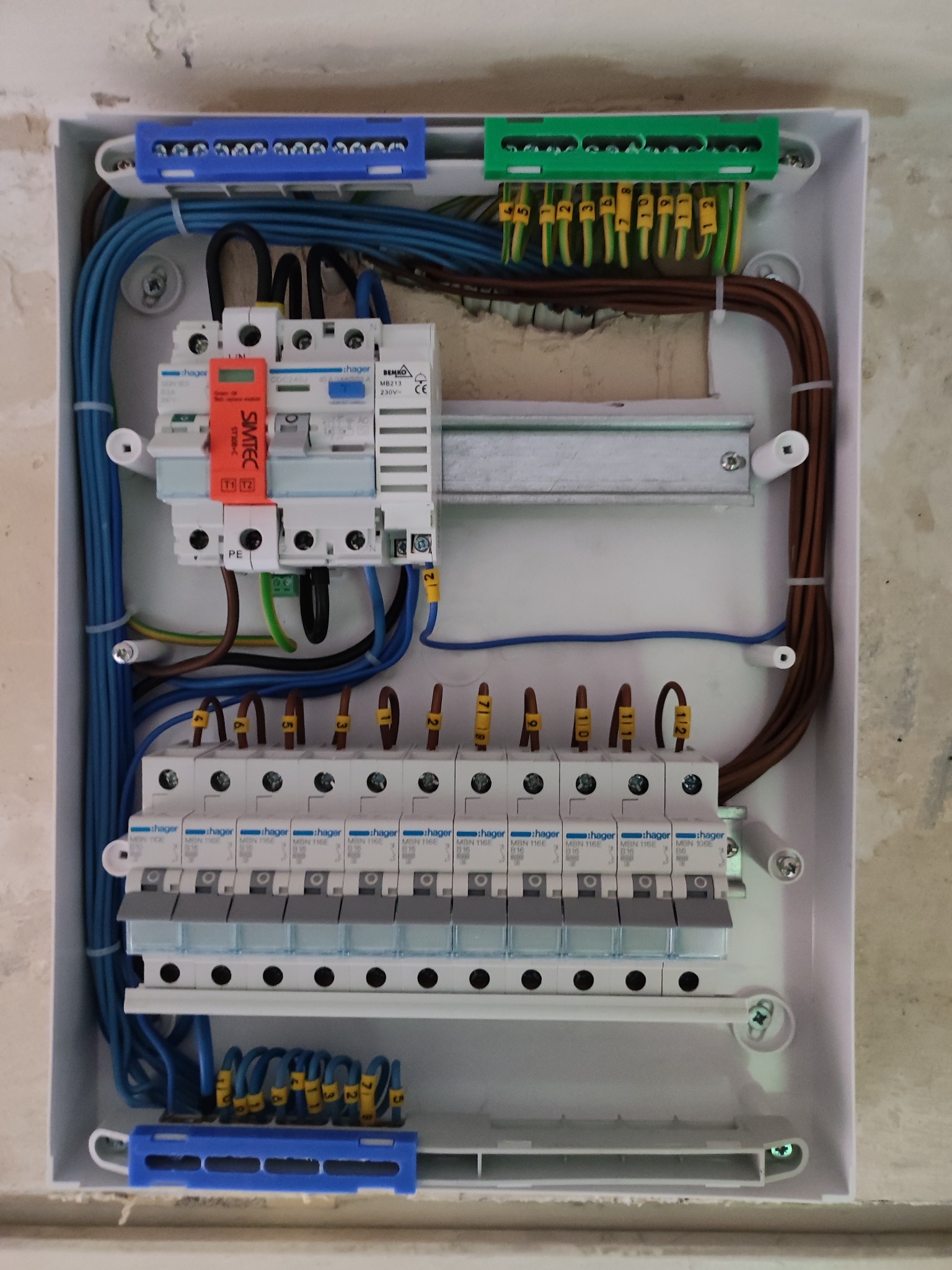 Rozdzielnica elektryczna Hager z zainstalowanymi bezpiecznikami i przewodami oznaczonymi numerami, widok z góry w trakcie montażu.