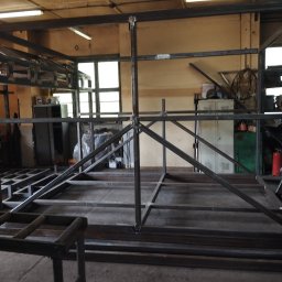 PAZ-MET PRZEMYSŁAW PAZIO - Konstrukcja metalowa spawana w warsztacie, widoczne spawy, profile stalowe tworzące szkielet, w tle okna i wyposażenie warsztatu.