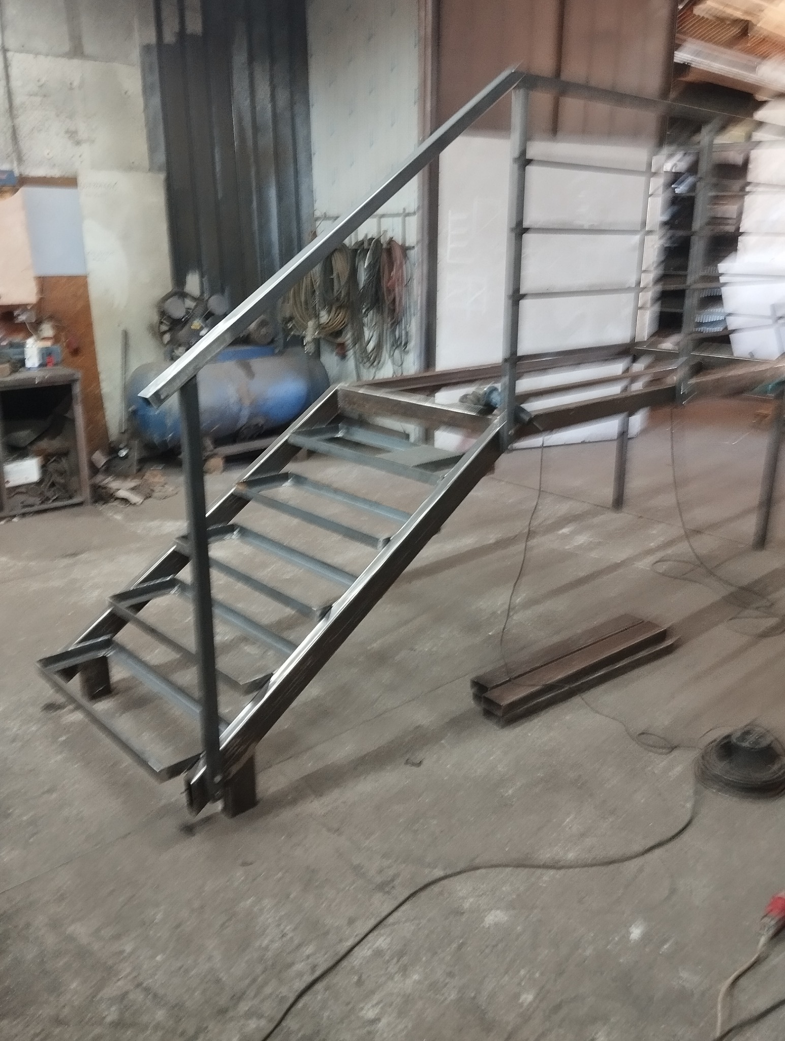 Konstrukcja schodów metalowych z poręczą w warsztacie, widoczny spawany szkielet i elementy do montażu.
