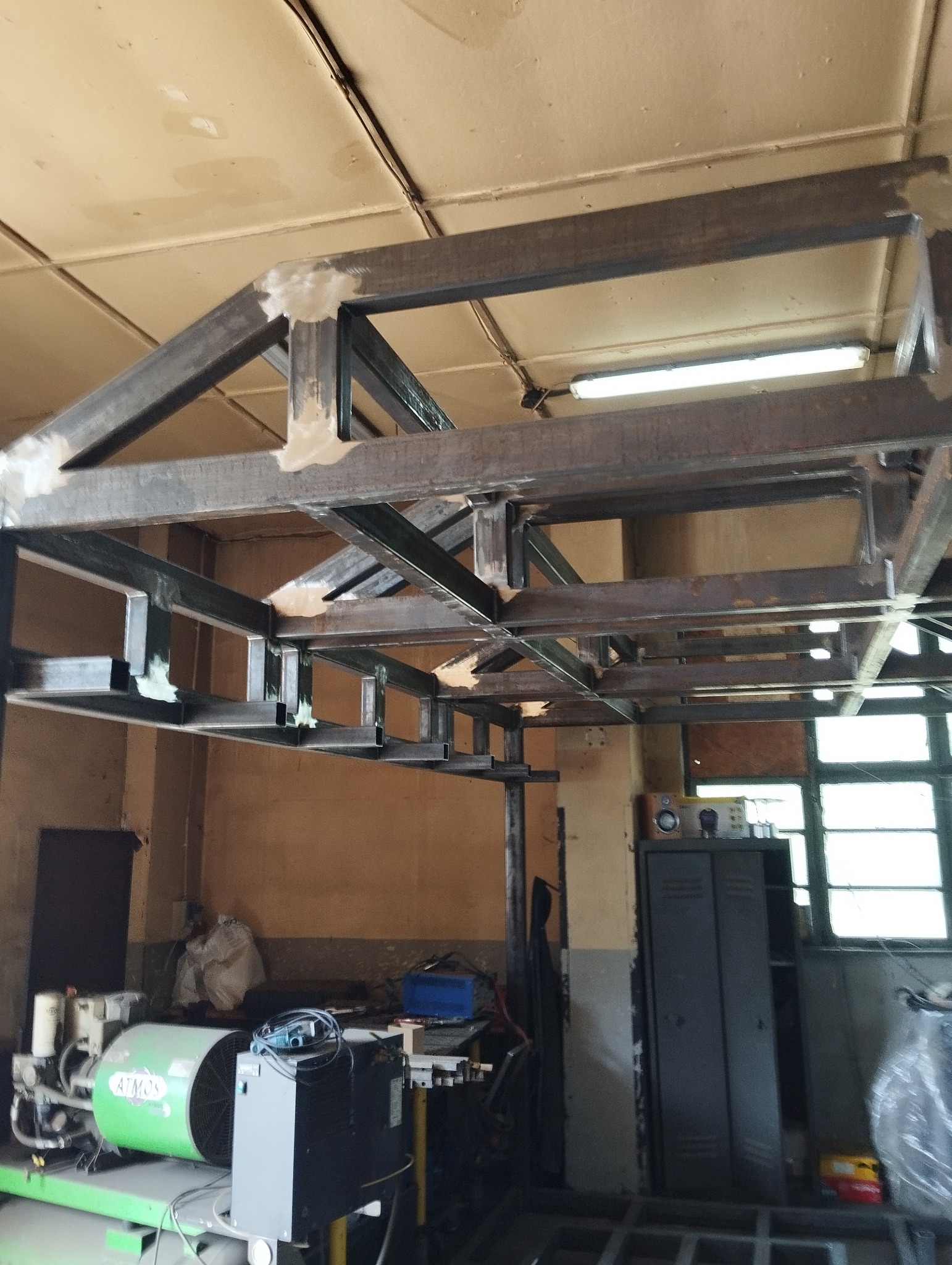 Szkielet stalowej konstrukcji spawanej, widoczne spoiny, w tle sprzęt warsztatowy, w tym kompresor ATMOS.