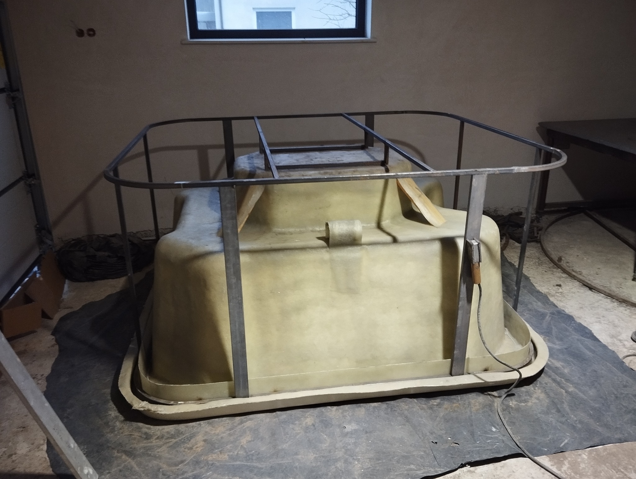 Forma z tworzywa sztucznego wzmocniona metalową ramą spawalniczą, widoczny spawacz z przewodem, przygotowana do dalszej obróbki w warsztacie.