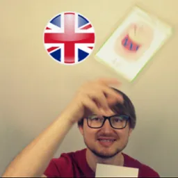 Mężczyzna w okularach rzuca kartą z rysunkiem bębna, obok flaga Wielkiej Brytanii.