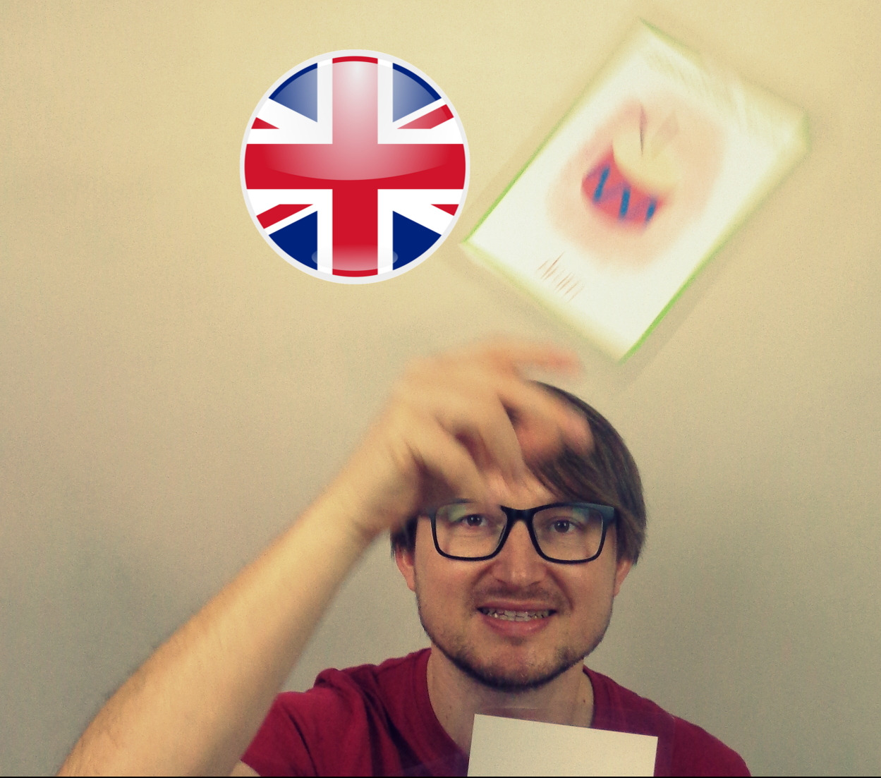 Mężczyzna w okularach rzuca kartą z rysunkiem bębna, obok flaga Wielkiej Brytanii.