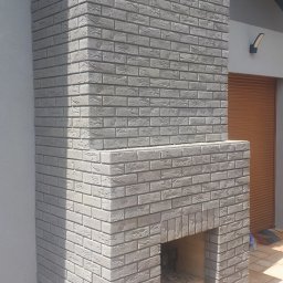 Kominek z otwartym paleniskiem na tarasie 
oklejony cegiełką elewacyjną