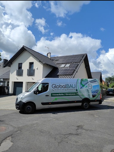 Srebrny van firmy GlobalBAU zaparkowany na ulicy przed domem z panelami słonecznymi na dachu, błękitne niebo z chmurami w tle.