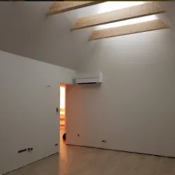 Poddasze po remoncie: świeżo pomalowane ściany w odcieniach bieli, drewniane belki stropowe, klimatyzator na ścianie, widoczne punkty elektryczne i jasna podłoga z paneli.