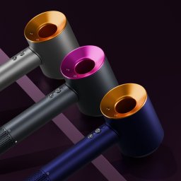 CRE8VISION - Trzy nowoczesne suszarki do włosów w kolorach: szarym ze złotym akcentem, czarnym z różowym i granatowym ze złotym, ułożone ukośnie na ciemnym tle z geometrycznym wzorem.