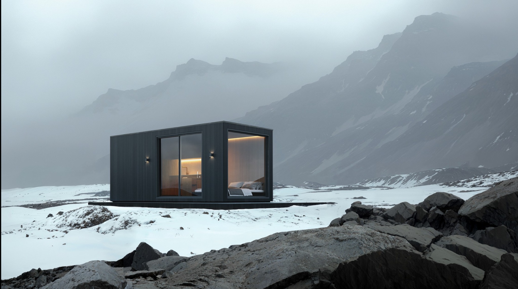 Minimalistyczny, ciemnoszary modułowy domek z dużymi oknami, oświetlony od wewnątrz, stoi na śniegu z kamieniami na tle mglistych gór.