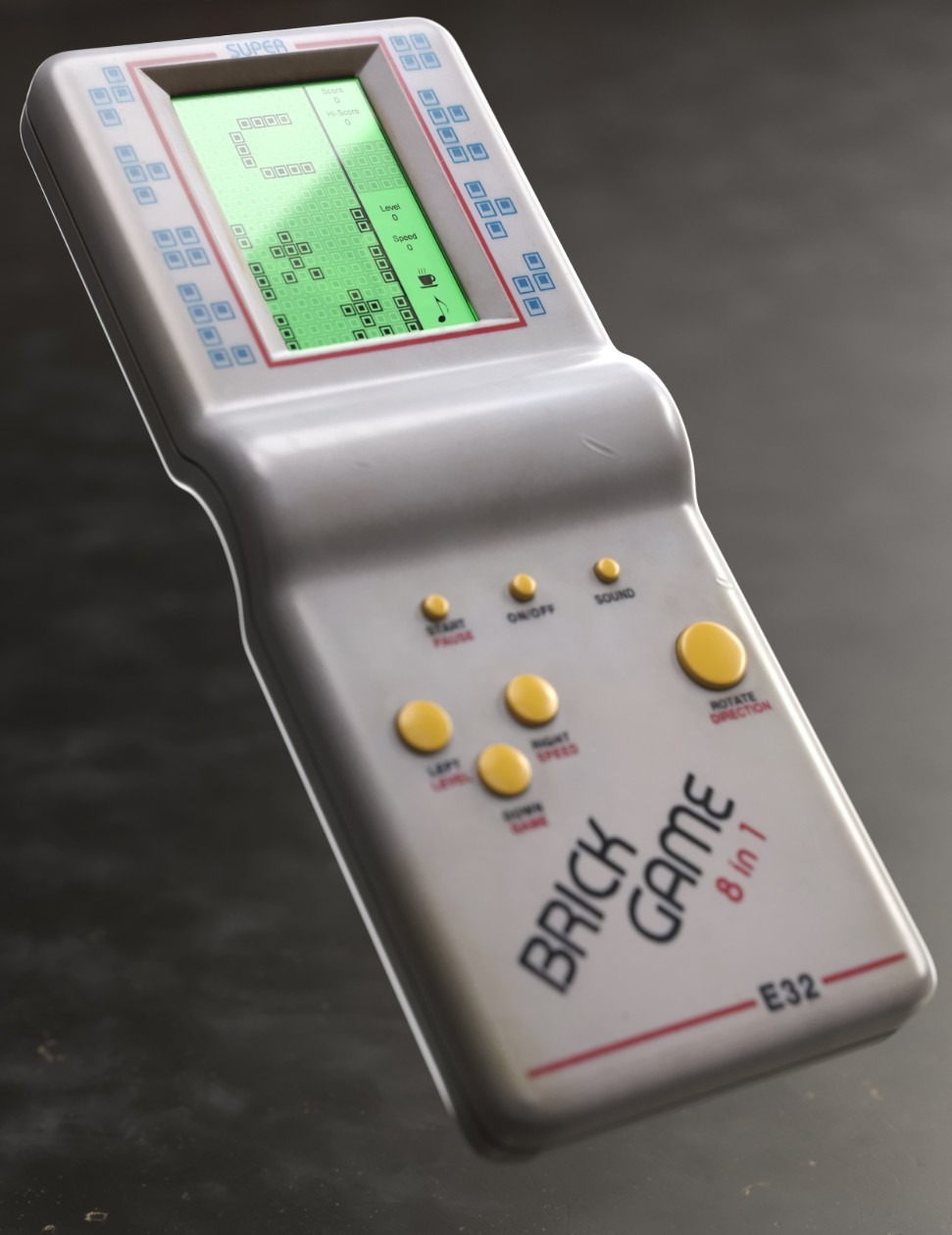 Retro przenośna konsola do gier Brick Game 8 in 1, wyświetlająca grę Tetris z klockami ułożonymi w kształcie filiżanki, widoczne przyciski sterujące i napis 'SUPER'.