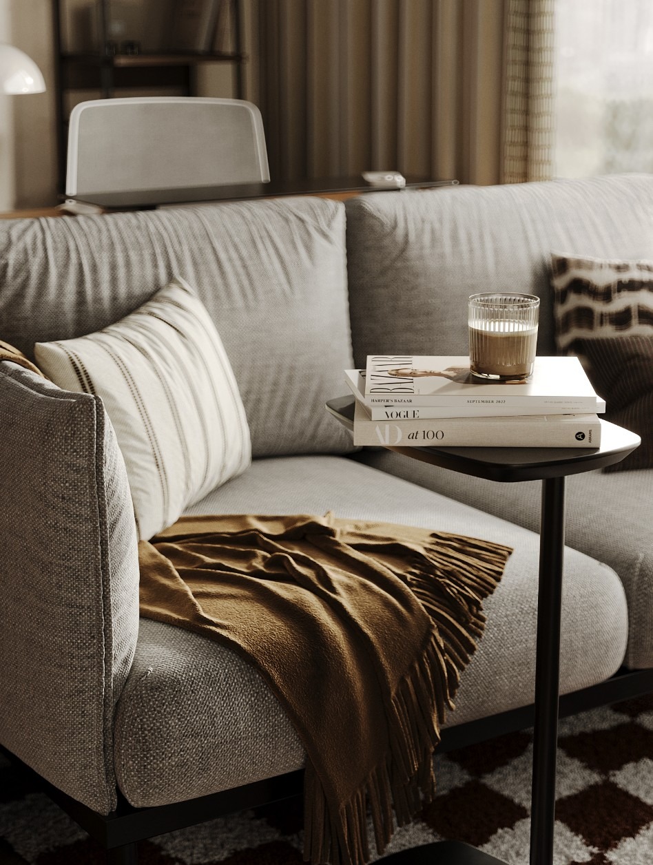 Neutralny salon z szarym narożnikiem, pledem w kolorze musztardowym, stolikiem kawowym, na którym leżą książki i stoi szklanka z kawą latte.