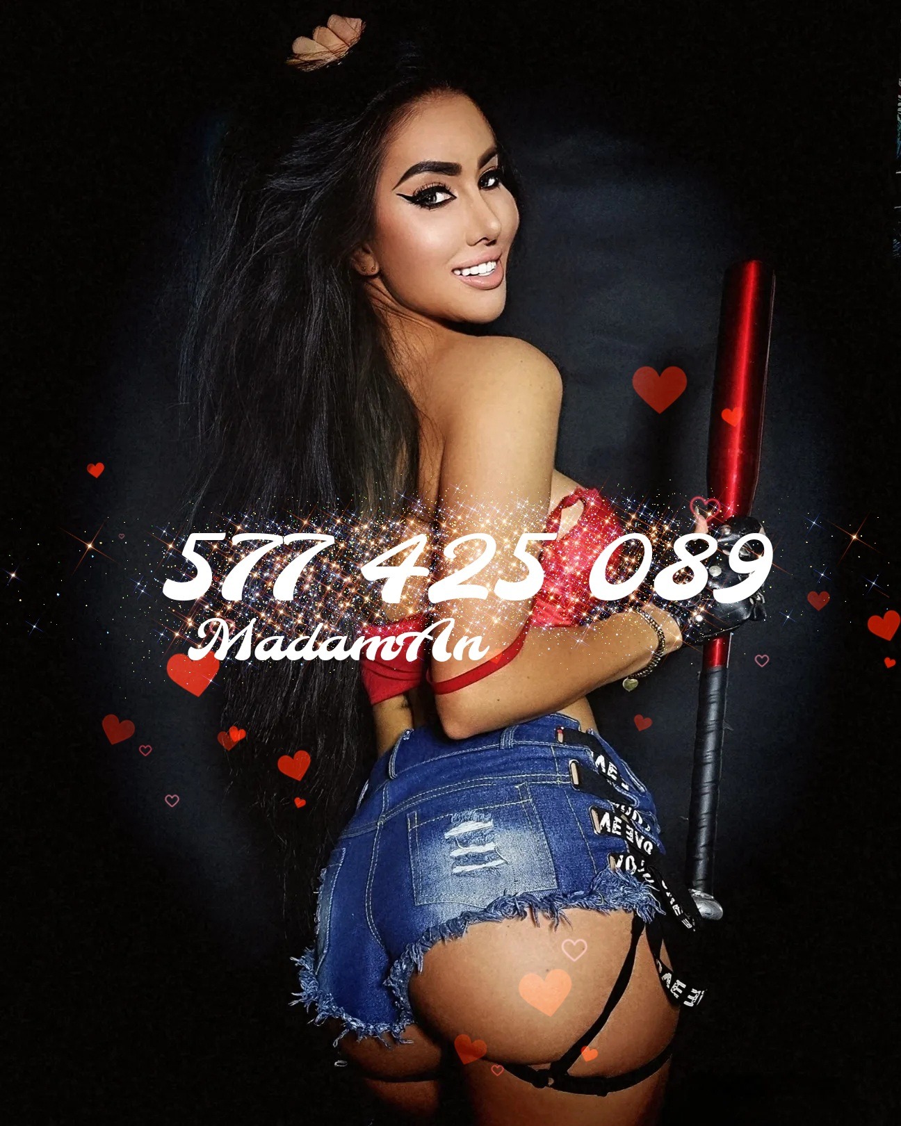 Uśmiechnięta kobieta z długimi włosami, w dżinsowych szortach, trzymająca kij bejsbolowy, na czarnym tle z sercami i błyszczącym tekstem.