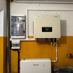 Nex Energy - Instalacja z białym falownikiem i magazynem energii SOFAR oraz rozdzielnicą PV-AC i PV-DC na żółto-białej ścianie w pomieszczeniu technicznym.