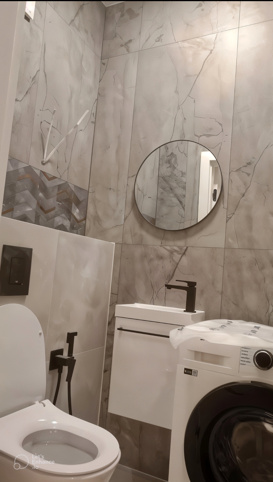 Nowoczesna łazienka z szarymi płytkami imitującymi marmur, okrągłym lustrem, białą szafką pod umywalką z czarną armaturą, toaletą z bidetką i pralką w folii ochronnej.