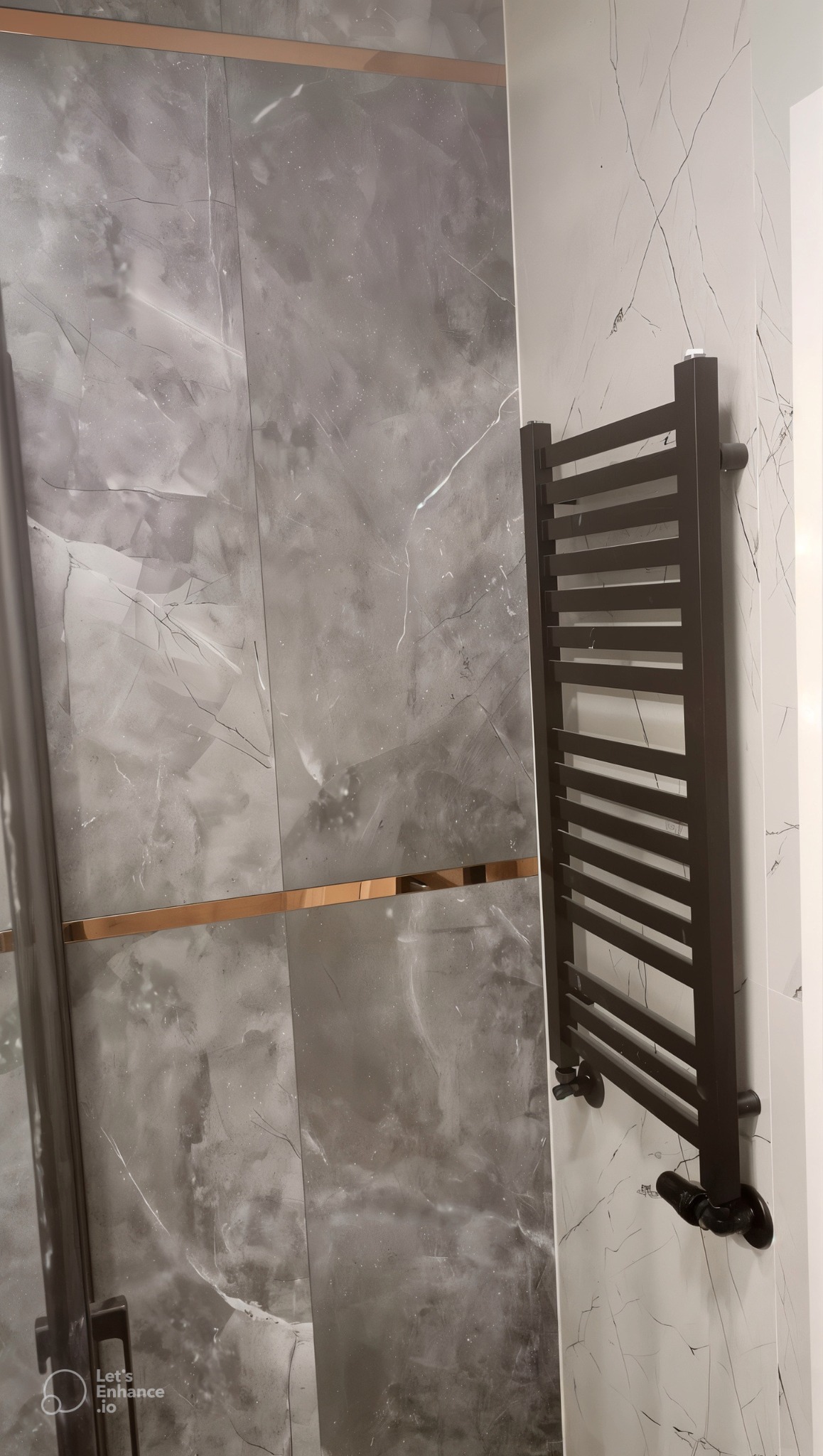 Nowoczesna łazienka z szarymi płytkami imitującymi marmur, akcentem w postaci złotej listwy i ciemnym grzejnikiem drabinkowym