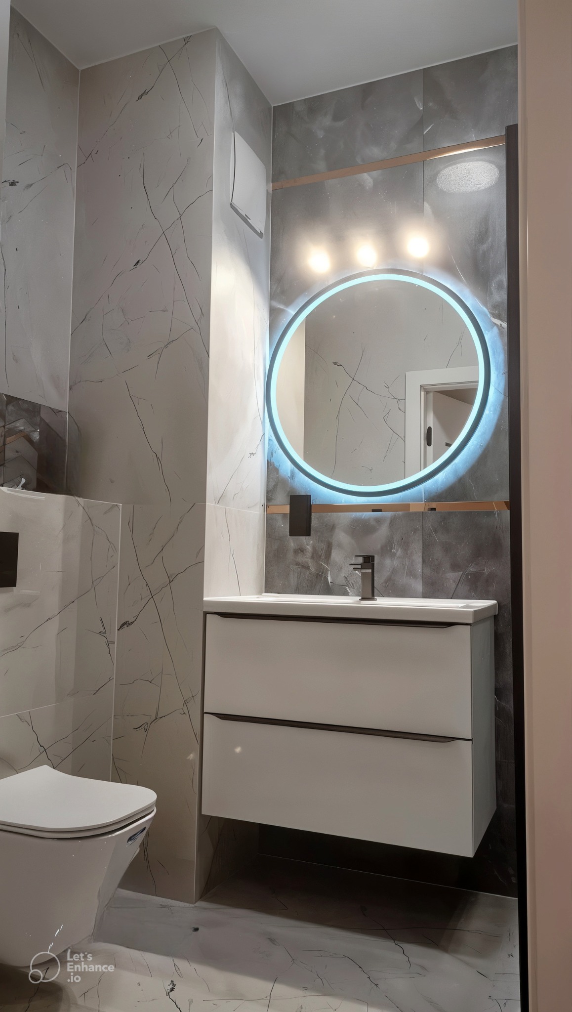 Nowoczesna łazienka z marmurowymi płytkami, okrągłym lustrem z podświetleniem LED, wiszącą szafką z umywalką i toaletą.