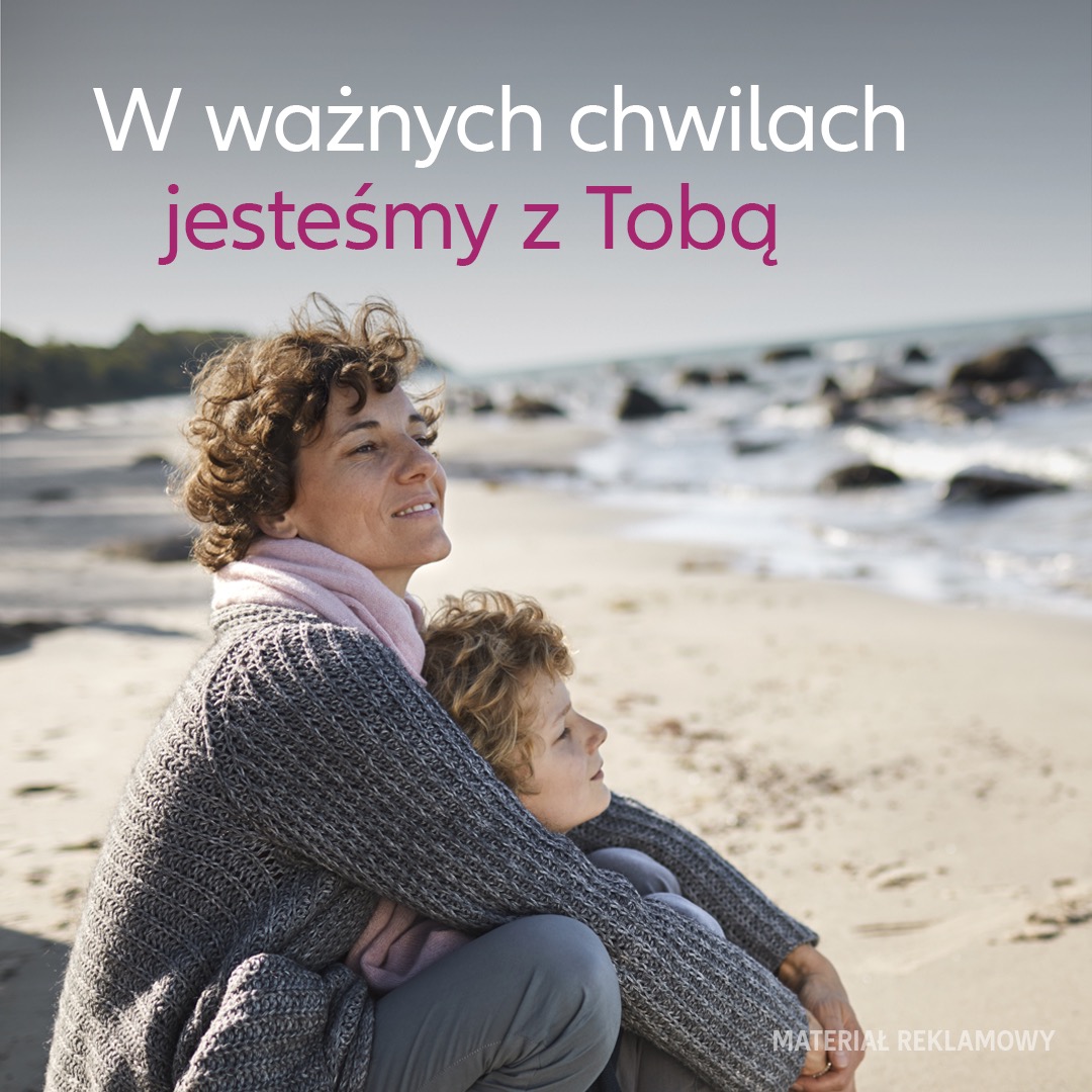 Matka z synem siedzą na piaszczystej plaży, wtuleni w siebie, patrzą w dal na morze; nad nimi napis 'W ważnych chwilach jesteśmy z Tobą'.