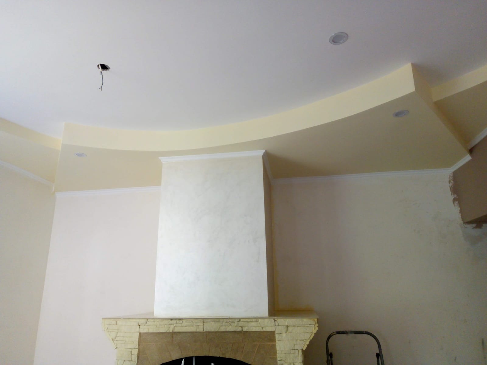 Ściana z imitacją kominka po nałożeniu dekoracyjnej struktury, widoczne wykończenia sufitu i fragment drabiny.