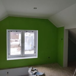 aleksander kowalski - Świeżo pomalowane na zielono poddasze z białym oknem PCV i fragmentem podłogi z płyty OSB, widoczne ślady po pracy.