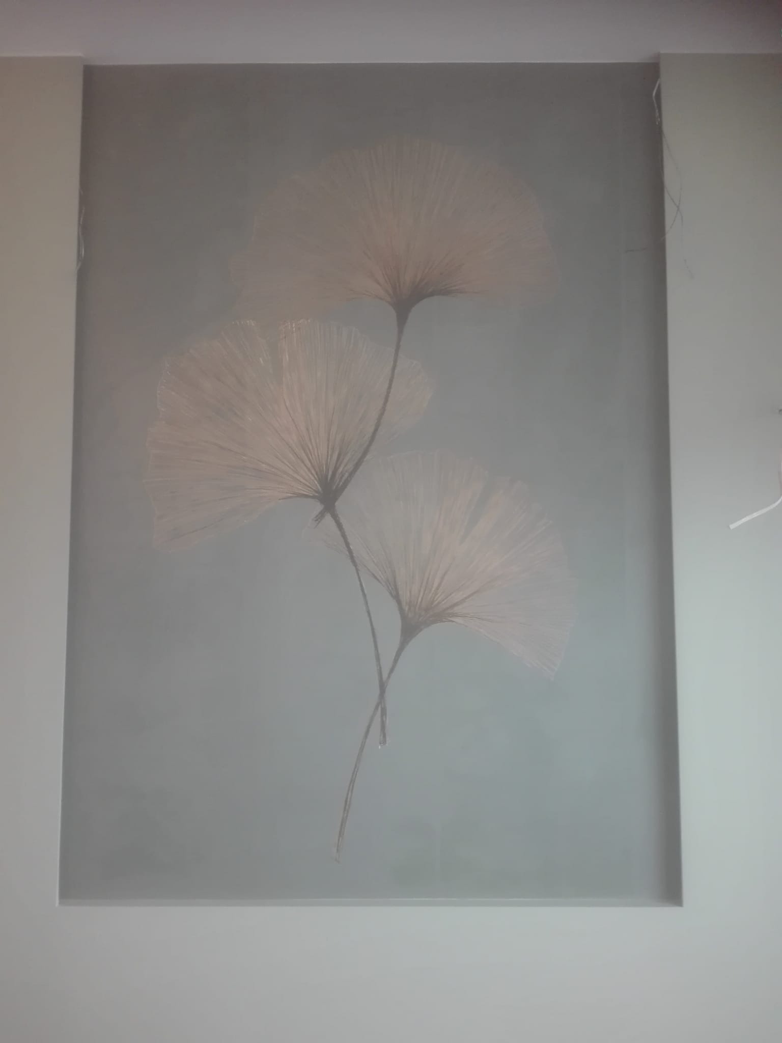 Dekoracyjna ściana w odcieniach szarości z motywem trzech stylizowanych, półprzezroczystych wachlarzy kwiatowych w kolorze pudrowego różu, otoczona białą ramą z widocznymi kablami w prawym górnym...